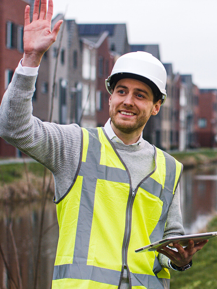 Man zwaaiend met veiligheidsvest en helm op.