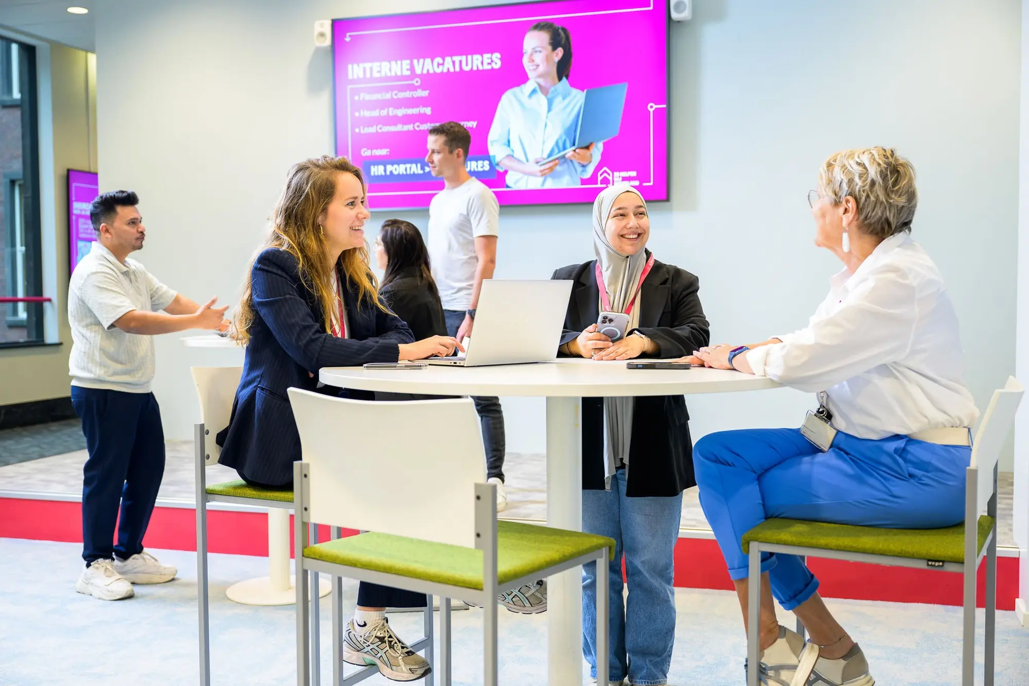 Drie mensen zittend aan een tafel in een open ruimte