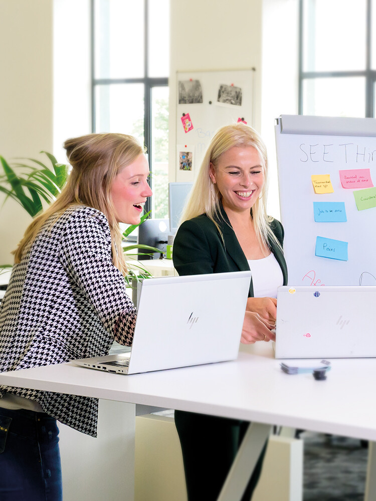 Twee mensen die samenwerken op een laptop
