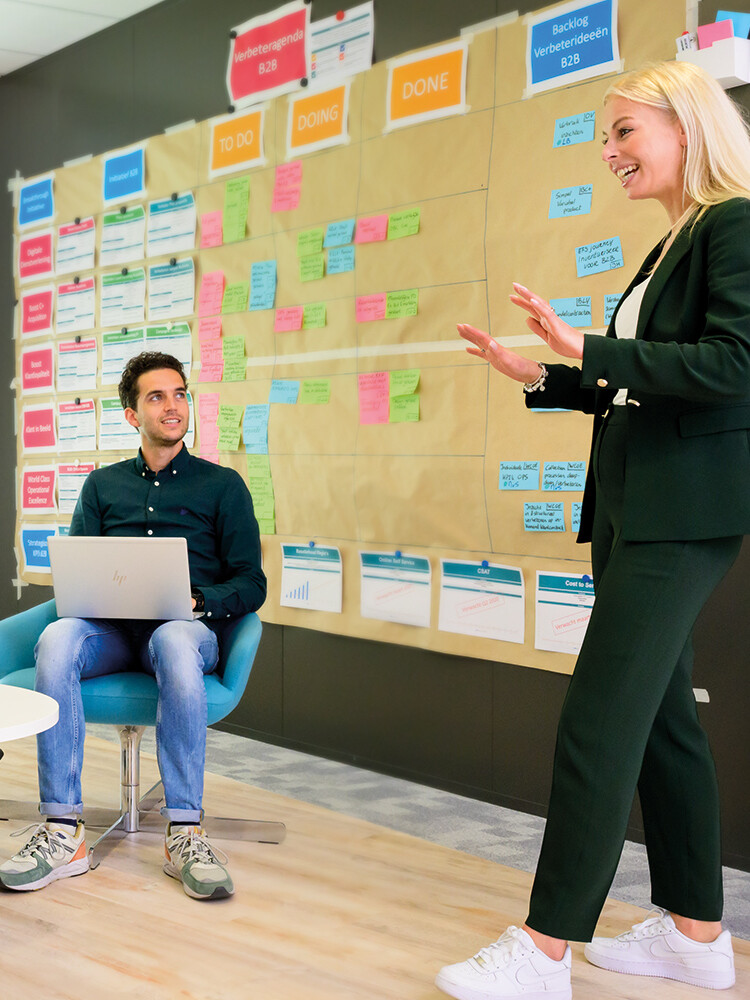 twee mensen tijdens een presentatie voor een muur vol met post-it's