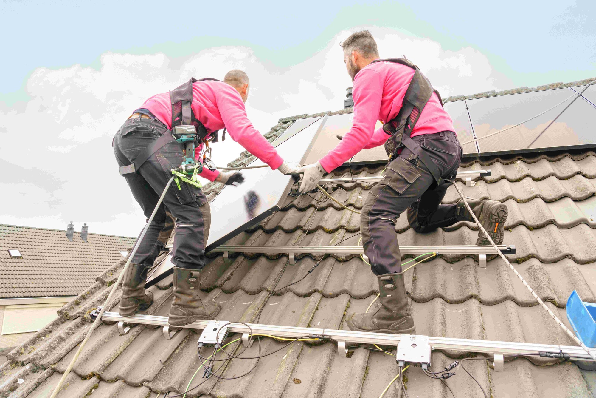 Twee monteurs op het dak die zonnepanelen plaatsen