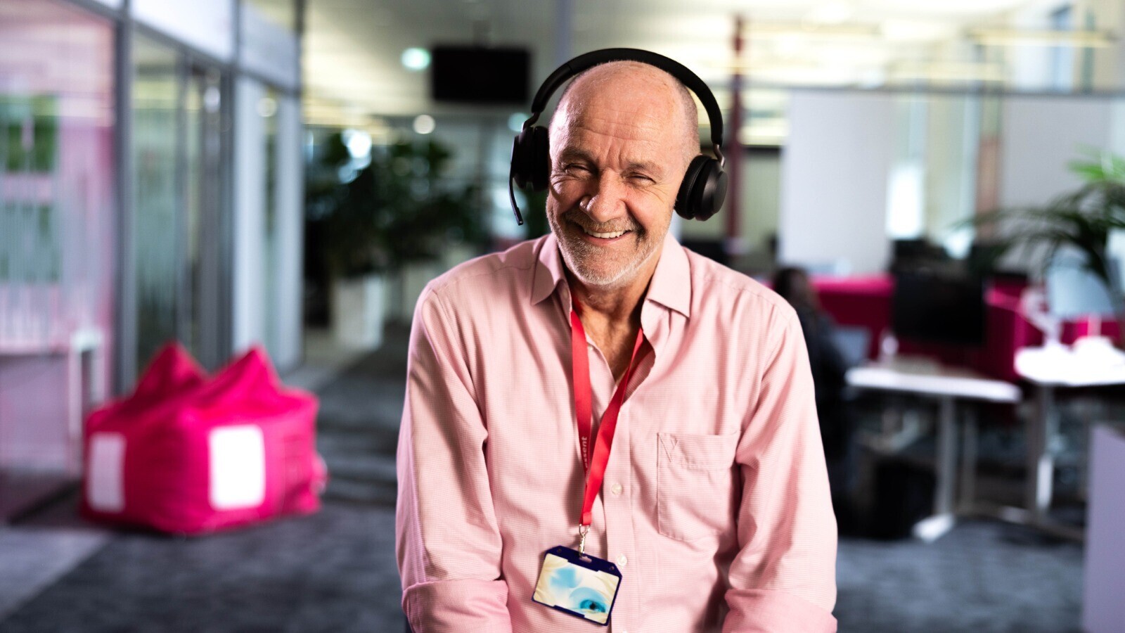 Lachende man in roze blouse met headset op