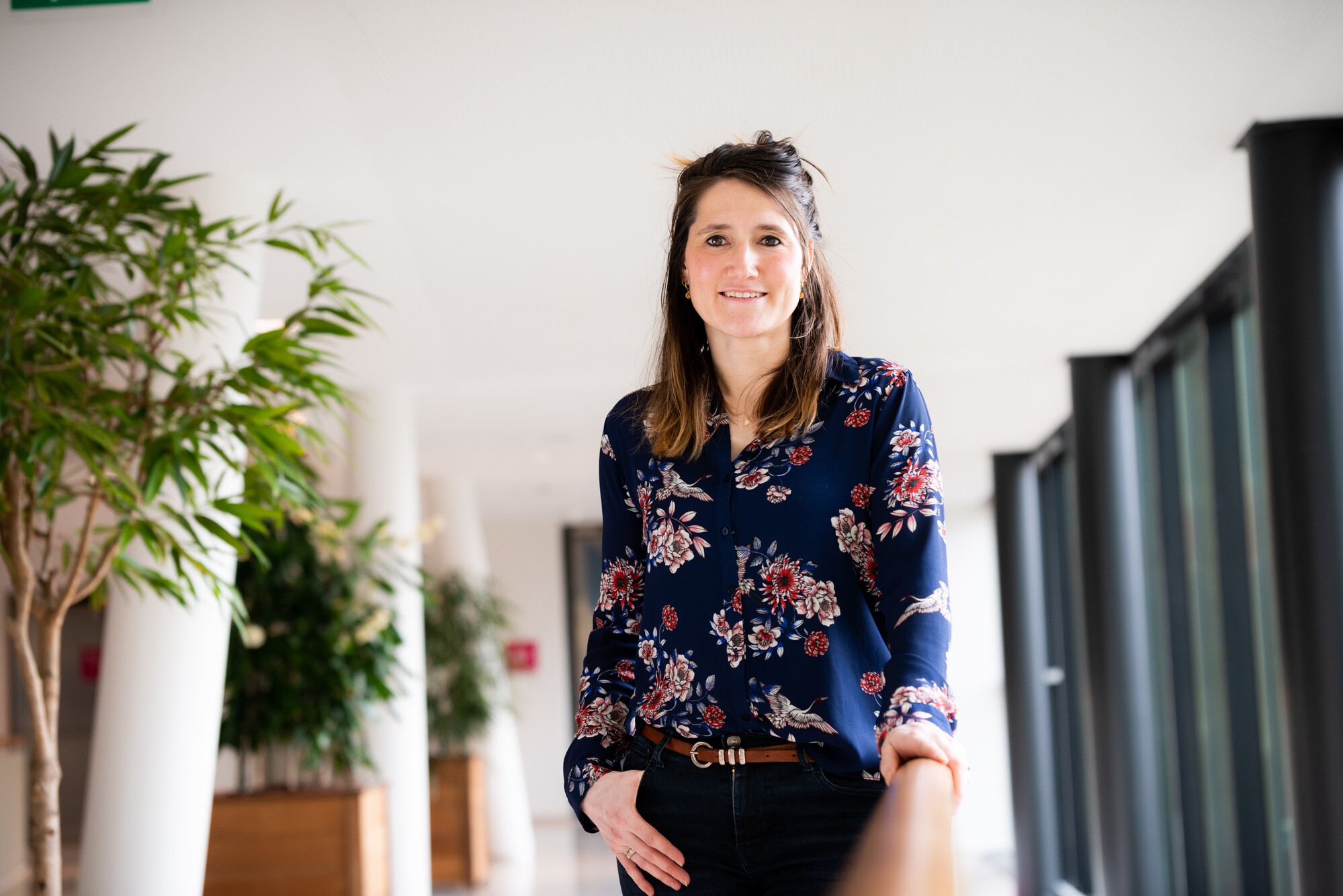 Vrouw staat met hand in zak in blauwe blouse met print