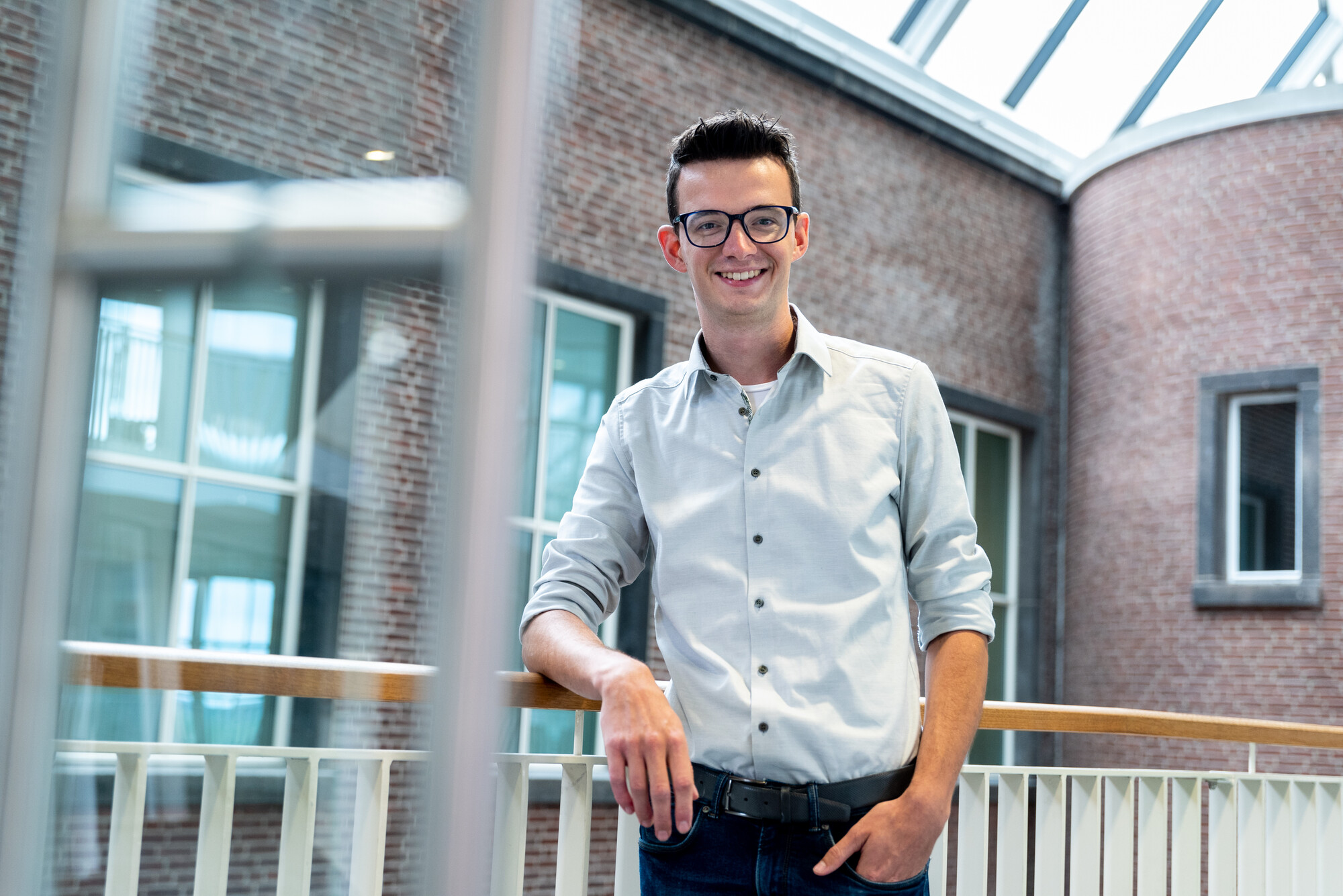 Man met bril leunend tegen de balustrade