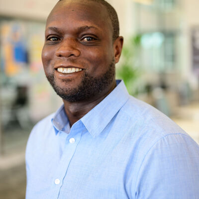 Man in lichtblauwe blouse lacht naar de camera