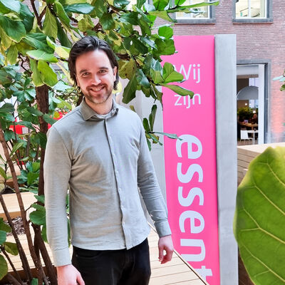 Man staat voor Essent bord en plant