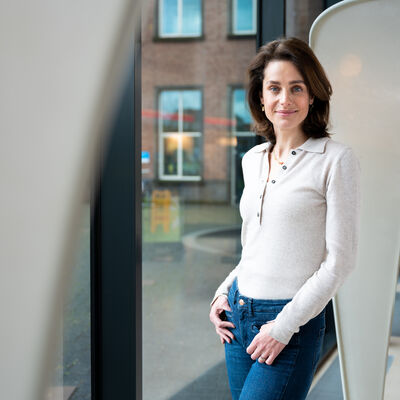 Vrouw glimlachend in camera voor een witte pilaar