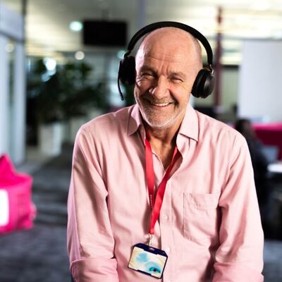 Lachende man in roze blouse met headset op