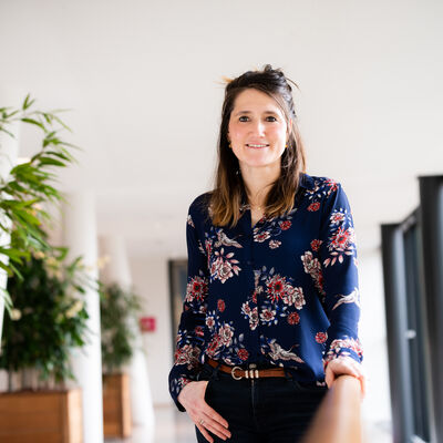 Vrouw staat met hand in zak in blauwe blouse met print