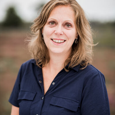 blonde vrouw met blauwe blouse kijkend in de camera