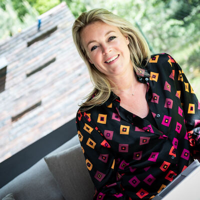 Vrouw met zwarte, roze, oranje blouse zittend achter laptop