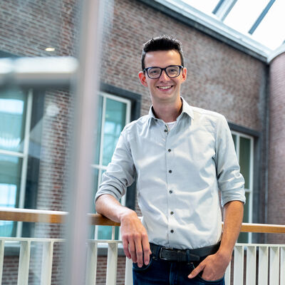 Man met bril leunend tegen de balustrade